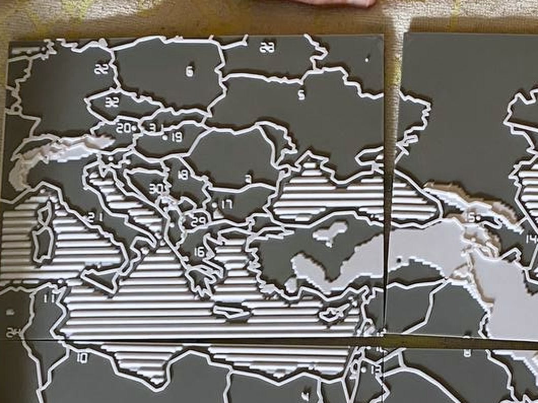 Close photograph of the first printed map: raised Arabic numerals such as 20, 19, 18, 30 and 16 sit inside the Central European and Balkan countries, next to ribbed seas and raised white borders.